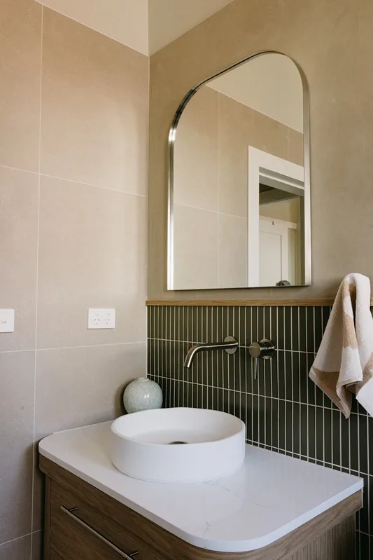 Timber vanity, arched mirror and green tiled splashback