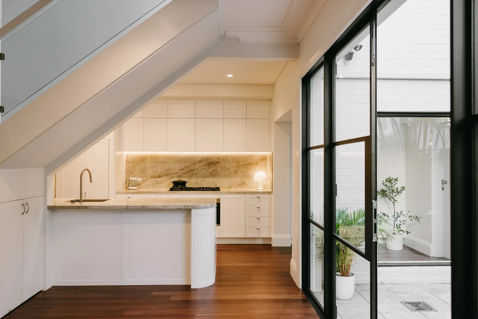 Renovated Paddington kitchen with stone splashback, peninsula and black aluminium french doors